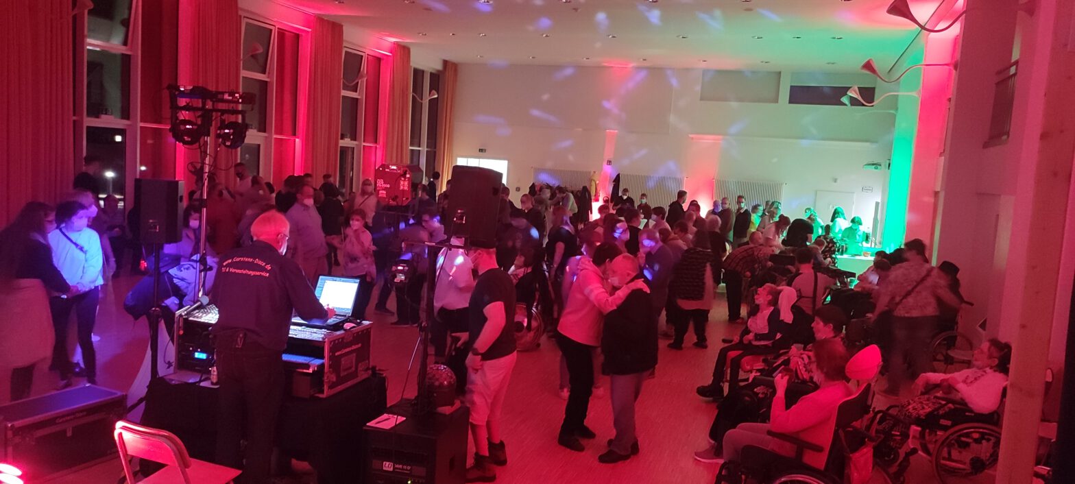 Menschen tanzen bei der ersten inklusiven HAI-Disco in der Aula der Waldschule Hatten